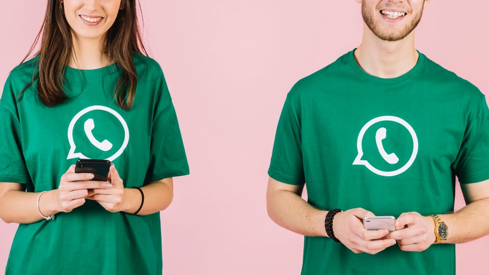 People using their phone wearing t-shirts with the WhatsApp logo